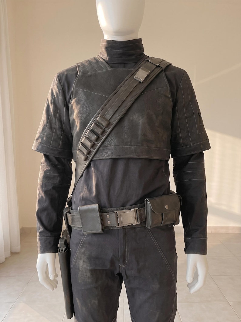 Pu&ograve; includere: Un set di costume tattico grigio scuro composto da una maglia a maniche lunghe con collo alto, un gilet a maniche corte e pantaloni abbinati. L'outfit include una tracolla diagonale con passanti, una cintura con tasche e una fondina.