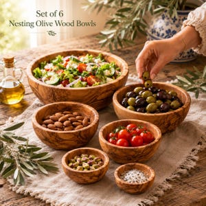 Könnte beinhalten: Ein Set aus 6 ineinander stapelbaren Olivenholzschalen in verschiedenen Größen mit natürlicher Holzmaserung. Die Schalen enthalten einen frischen Salat, grüne und schwarze Oliven, Mandeln, Kirschtomaten, Pistazien und Meersalz, mit dem Text Set of 6 Nesting Olive Wood Bowls.