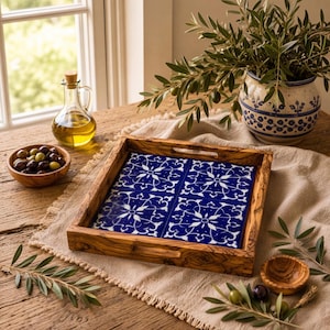 May include: A square wooden serving tray featuring four blue and white ceramic tiles with a symmetrical floral pattern. The tray has integrated handles on two sides and is crafted from wood with a visible grain. The tiles are arranged in a grid.