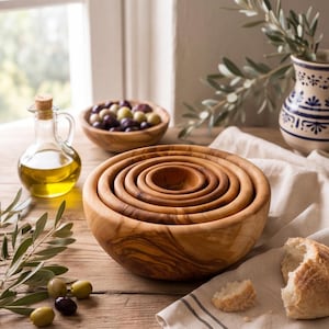 Peut inclure: Un ensemble de cinq bols ronds en bois emboîtés les uns dans les autres, présentant un motif de grain naturel. Les bols sont fabriqués en bois brun clair avec des détails de grain tourbillonnants plus foncés, offrant une surface lisse et incurvée.