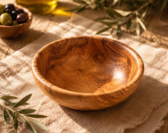 May include: A round wooden bowl featuring a distinct natural grain pattern with swirling light and dark brown tones. The bowl has a smooth, polished interior surface and a curved rim, showcasing the organic texture and warm color of the wood.