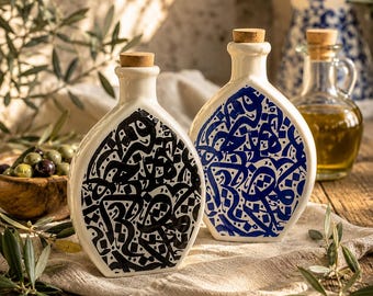Puede incluir: Dos botellas de cerámica blanca con tapones de corcho, cada una con intrincados patrones de caligrafía en negro o azul. Las botellas tienen una forma plana y redondeada y están colocadas en posición vertical, mostrando diseños de escritura.