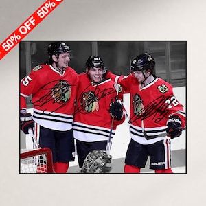 Op de afbeelding: Een foto van drie ijshockeyspelers in rood-wit-zwarte Chicago Blackhawks-shirts met zwarte helmen en handschoenen. De spelers vieren feest op het ijs en de afbeelding bevat drie duidelijke handtekeningen in zwarte inkt op de shirts.