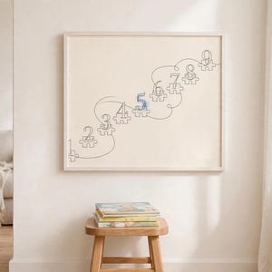 以下が含まれることがあります： 斜め上に並んだパズルのピースの連続線画が描かれた額入りウォールプリント。各ピースには1から9までの数字が記されており、数字の5は青いインクで強調されています。