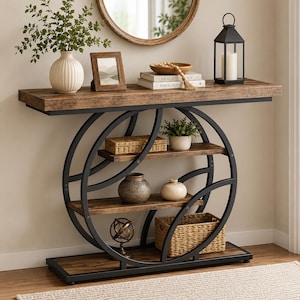 May include: A console table with a rectangular wood-grain top and base, featuring a black metal frame with two large intersecting circular supports. The table includes two interior shelves holding a woven basket, a ceramic vase, and a metal sphere.