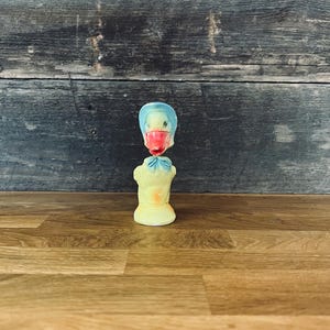 Peut inclure: Figurine de canard vintage avec une tête bleue, un bec rouge et un corps jaune. Le canard a un design classique et est probablement en caoutchouc ou en plastique. La figurine est posée sur une surface en bois.