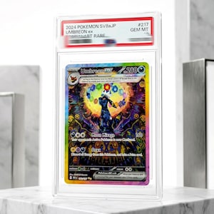 Può includere: Una carta collezionabile Pokemon SV8aJP Umbreon ex del 2024, classificata e sigillata in una custodia di plastica trasparente. La carta presenta un'illustrazione colorata e dettagliata del personaggio Umbreon circondato da gemme.