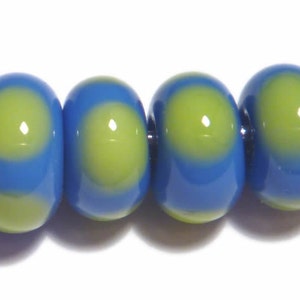 May include: Close-up of four blue and green glass beads. Each bead has a central green circle surrounded by a blue gradient. The beads are smooth and glossy, with a slight oval shape. The beads are strung together.