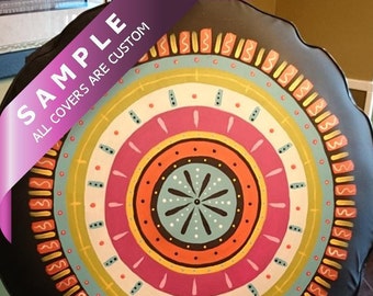 May include: A black round chair cushion with a colorful mandala design. The design features concentric circles in shades of pink, orange, yellow, blue, and green. The text "SAMPLE ALL COVERS ARE CUSTOM" is visible in the upper left corner of the image.