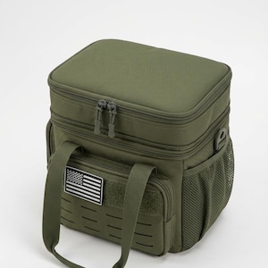 May include: An olive green tactical lunch bag featuring a rectangular shape, a top zippered compartment, and a front pocket with a hook-and-loop patch displaying a black and white American flag. It includes side mesh pockets and carry handles.