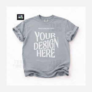 May include: A light gray short-sleeve t-shirt with a crew neckline and rolled sleeves. The center of the shirt features the white text "TRUE FORM MOCKUPS" and "YOUR DESIGN HERE" in a bold, stylized font, with smaller text printed below.