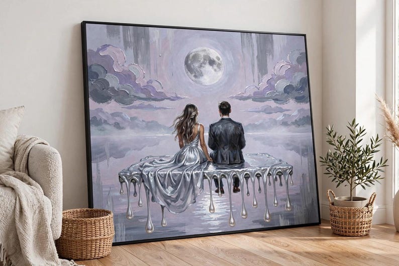 A large, unframed oil painting of a couple on a dripping silver platform under a full moon is displayed on a wooden floor next to a woven basket and a potted plant.