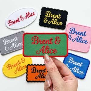 May include: A collection of embroidered fabric patches in various shapes and colours, each featuring the text Brent & Alice. The shapes include rectangles, ovals, and scalloped-edge rectangles in white, black, grey, green, pink, yellow, orange, and blue.