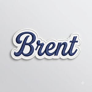 以下が含まれることがあります： 濃いネイビーブルーの筆記体フォントで「Brent」という名前が刺繍されたワッペン。文字はテキストの形状に沿った太い白い縁取りで囲まれており、布製アップリケとしてすっきりと明確な輪郭を作り出しています。