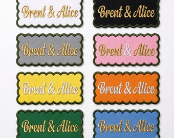 Naampatch op maat: elegant gouden lettertype, geborduurde geschulpte rand, opstrijkbaar of opnaaibaar.