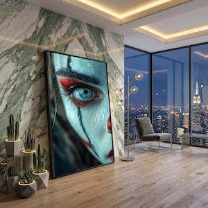 Può includere: Una grande stampa artistica incorniciata che mostra il primo piano di un volto con pelle pallida, occhi azzurri luminosi e accenti di trucco rosso intorno agli occhi e alle labbra. L'opera è esposta in una stanza con pareti in marmo.