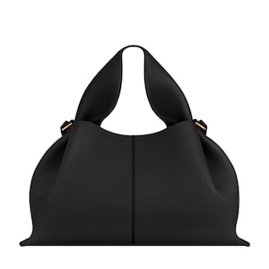 May include: A black leather handbag with a pebbled texture, featuring a wide, integrated handle design that creates a soft, gathered silhouette. The bag includes a vertical center seam and small metallic hardware accents on the sides.