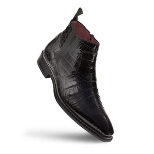 Könnte beinhalten: Ein schwarzer Stiefeletten-Schuh mit glänzender, texturierter Oberfläche, die an Krokodilleder erinnert. Der Schuh hat eine spitz zulaufende Kappe, einen seitlichen Reißverschluss, einen kleinen Absatz und eine dunkle Stofflasche am Schaftrand.