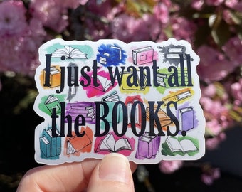 Può includere: Un adesivo bianco con uno sfondo colorato di libri e il testo "I just want all the BOOKS!"