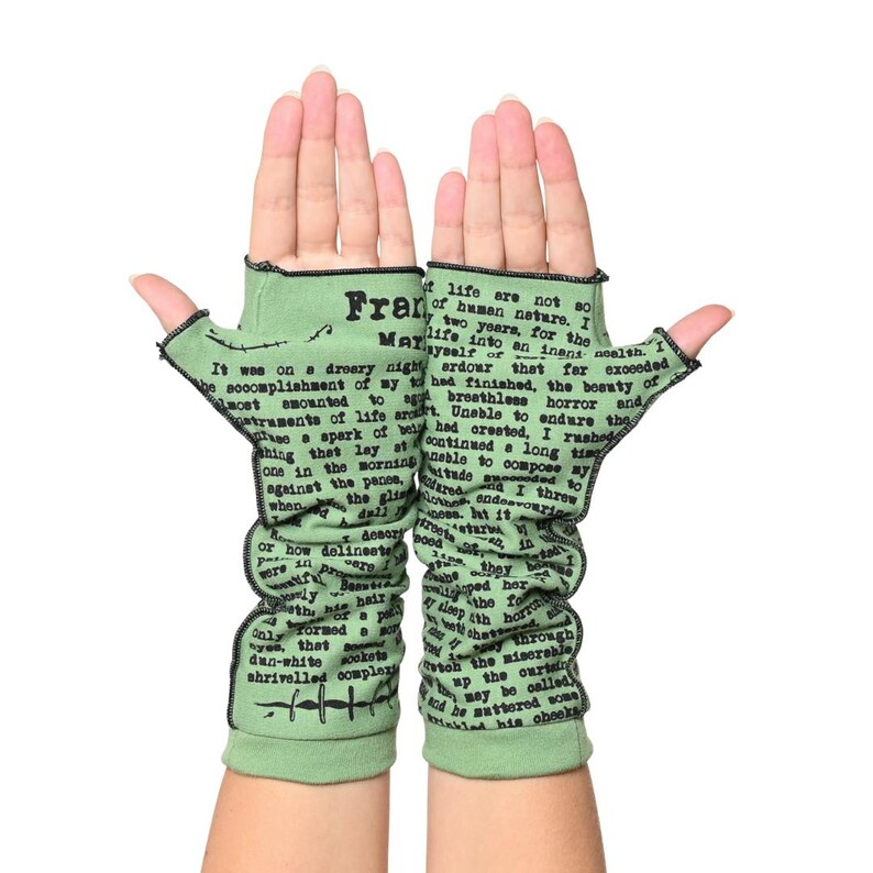 Puede incluir: Un par de guantes sin dedos de color verde claro con costuras negras. Los guantes presentan texto impreso de una novela, con la palabra "Frank" visible. Los guantes est&aacute;n dise&ntilde;ados para cubrir la mano y el antebrazo.