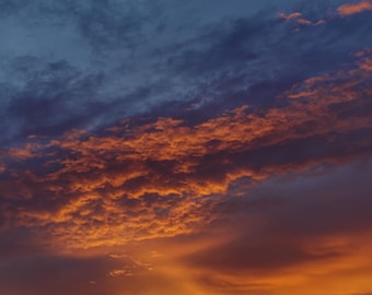 Fotografía digital imprimible de una vibrante puesta de sol con nubes doradas y anaranjadas.