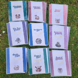 May include: A collection of nine rectangular cards with white centers and colored borders. Each card features a unique title and a small illustration, including titles like Monstrous Regiment, Unbroken Slumber, Hunger Games, The Iron Curtain, The Widening Gyre, Lemming Jeopardy, Gentle Night, Sugar & Spice, and Court of Miracles.