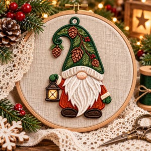 May include: A circular wooden embroidery hoop containing a fabric panel with a stitched gnome design. The gnome wears a green hat decorated with brown pinecones and green needles, a white beard, and a red coat, while holding a small lantern.