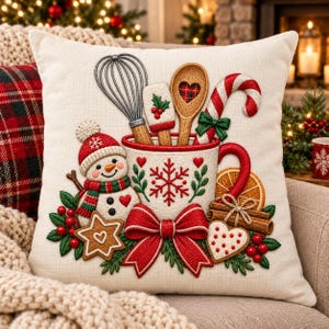 May include: A square off-white throw pillow featuring an embroidered design of a white mug filled with a whisk, spatula, wooden spoon, and candy cane. A snowman, gingerbread cookies, cinnamon sticks, orange slices, and a red bow decorate the front.