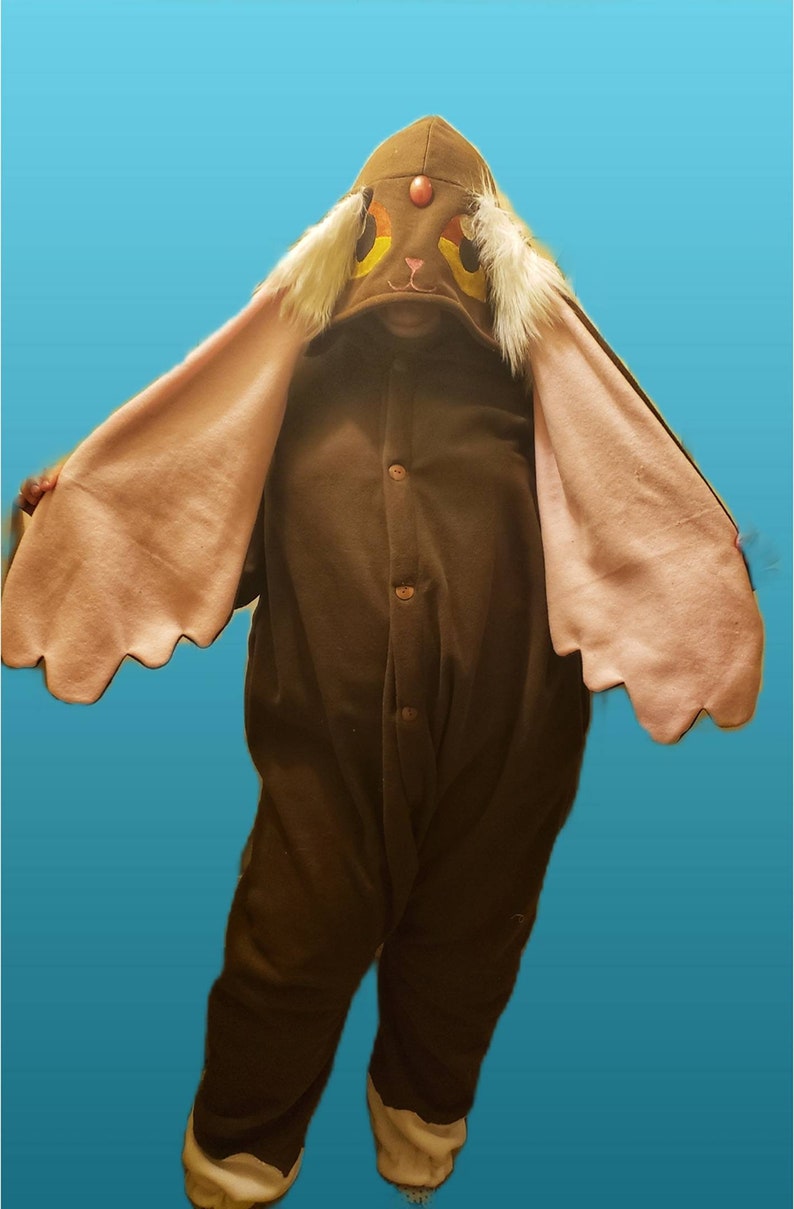 May include: Brown plush jumpsuit with a large hood featuring a cartoon bunny face with pink ears. The hood has a red nose and yellow eyes.