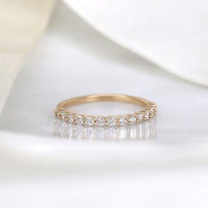 May include: A delicate gold band ring with a row of small, clear diamonds set in a pave setting.