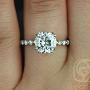 May include: A silver engagement ring with a large, round, clear center stone and smaller, clear stones set in a pave band.