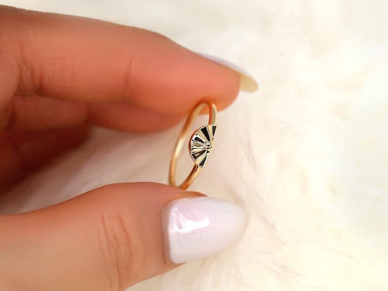 May include: A gold ring featuring a fan-shaped design. The ring is simple and elegant.