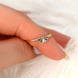 May include: A gold ring featuring a fan-shaped design. The ring is delicate and has a simple, elegant style.