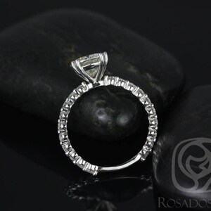 May include: A silver engagement ring with a large, square-cut diamond center stone and a band of smaller diamonds. The ring is set on a black background.