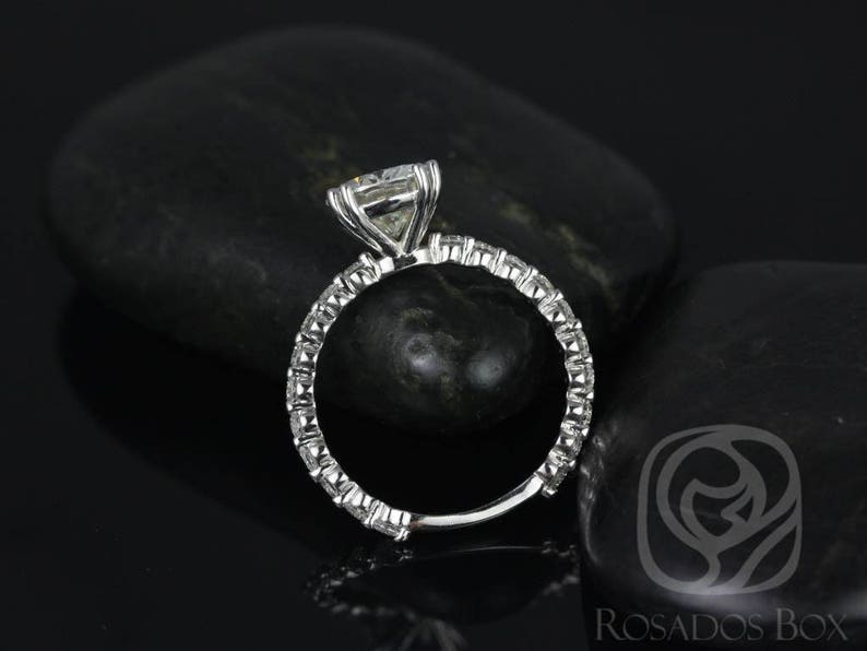 May include: A silver engagement ring with a large, square-cut diamond center stone and a band of smaller diamonds. The ring is set on a black background.