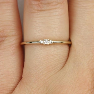 May include: A delicate gold band ring with three small diamonds set in a row.