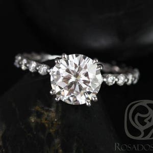 May include: A silver engagement ring with a large, round, clear diamond center stone and a pave diamond band.