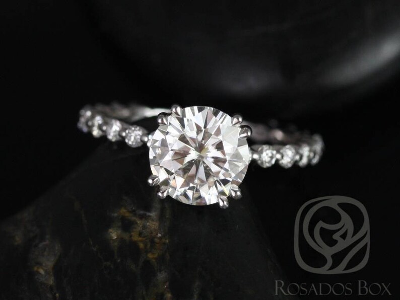 May include: A silver engagement ring with a large, round, clear diamond center stone and a pave diamond band.