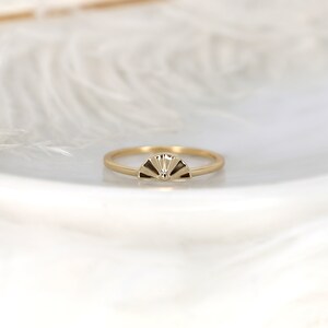 May include: A gold ring featuring a fan-shaped design. The ring is simple and elegant.