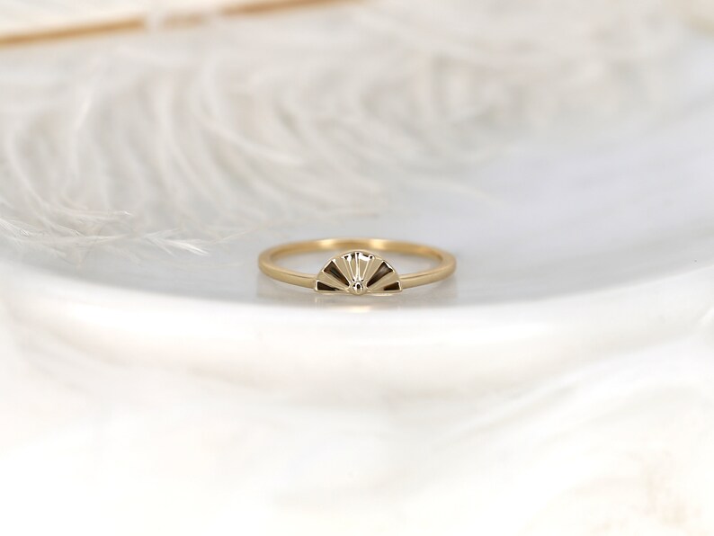 May include: A gold ring featuring a fan-shaped design. The ring is simple and elegant.