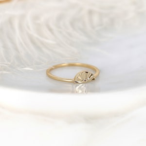 May include: A gold ring featuring a sunburst design. The ring is simple and delicate, making it ideal for everyday wear.