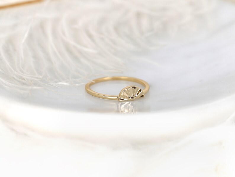 May include: A gold ring featuring a sunburst design. The ring is simple and delicate, making it ideal for everyday wear.