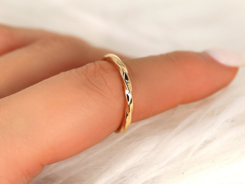 May include: A thin gold band ring with a twisted, textured design.