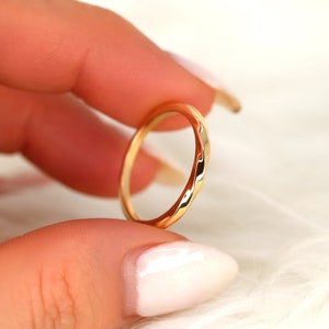 May include: A thin gold band ring with a hammered texture.