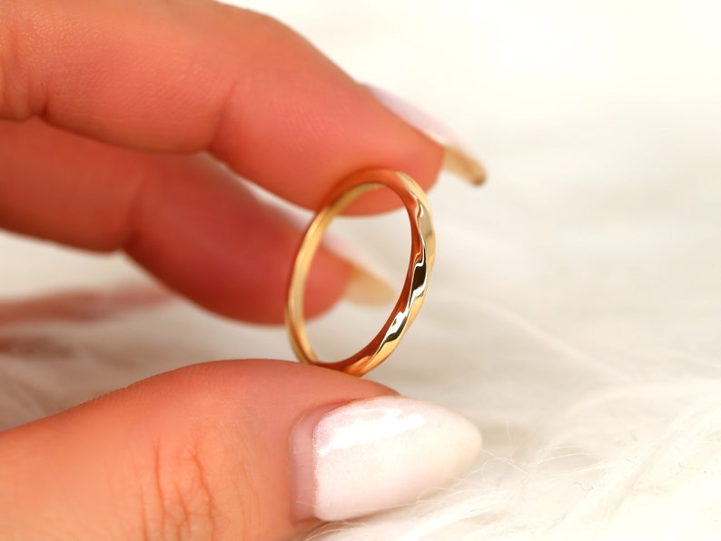 May include: A thin gold band ring with a hammered texture.