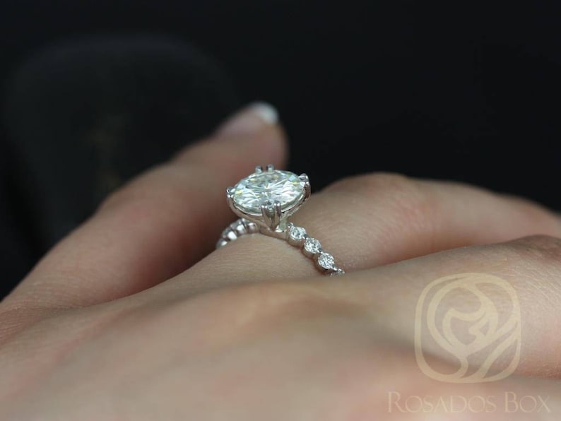 May include: A silver engagement ring with a large oval-shaped diamond and a band of smaller diamonds.