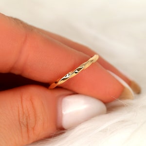 May include: A thin gold band ring with a twisted design.