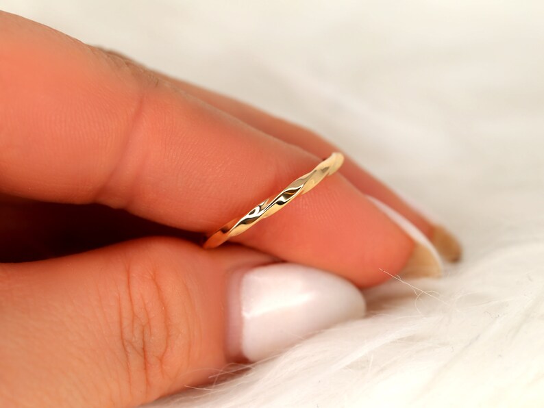 May include: A thin gold band ring with a twisted design.