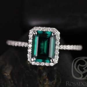 May include: A silver ring with a large emerald green gemstone surrounded by a halo of smaller diamonds.