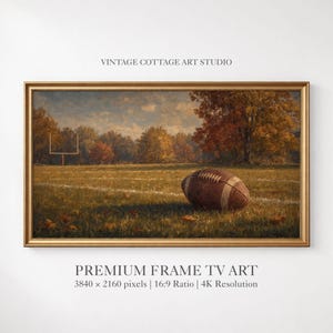 May include: A landscape painting in a gold frame depicting a brown football resting on a grassy field with white yard lines and a goalpost. The background features autumn trees with orange and yellow foliage under a cloudy sky. Text reads VINTAGE COTTAGE ART STUDIO and PREMIUM FRAME TV ART 3840 x 2160 pixels 16:9 Ratio 4K Resolution.